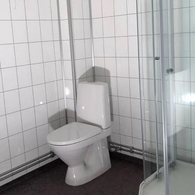 Gulvmontert toalett ved glassvegg.